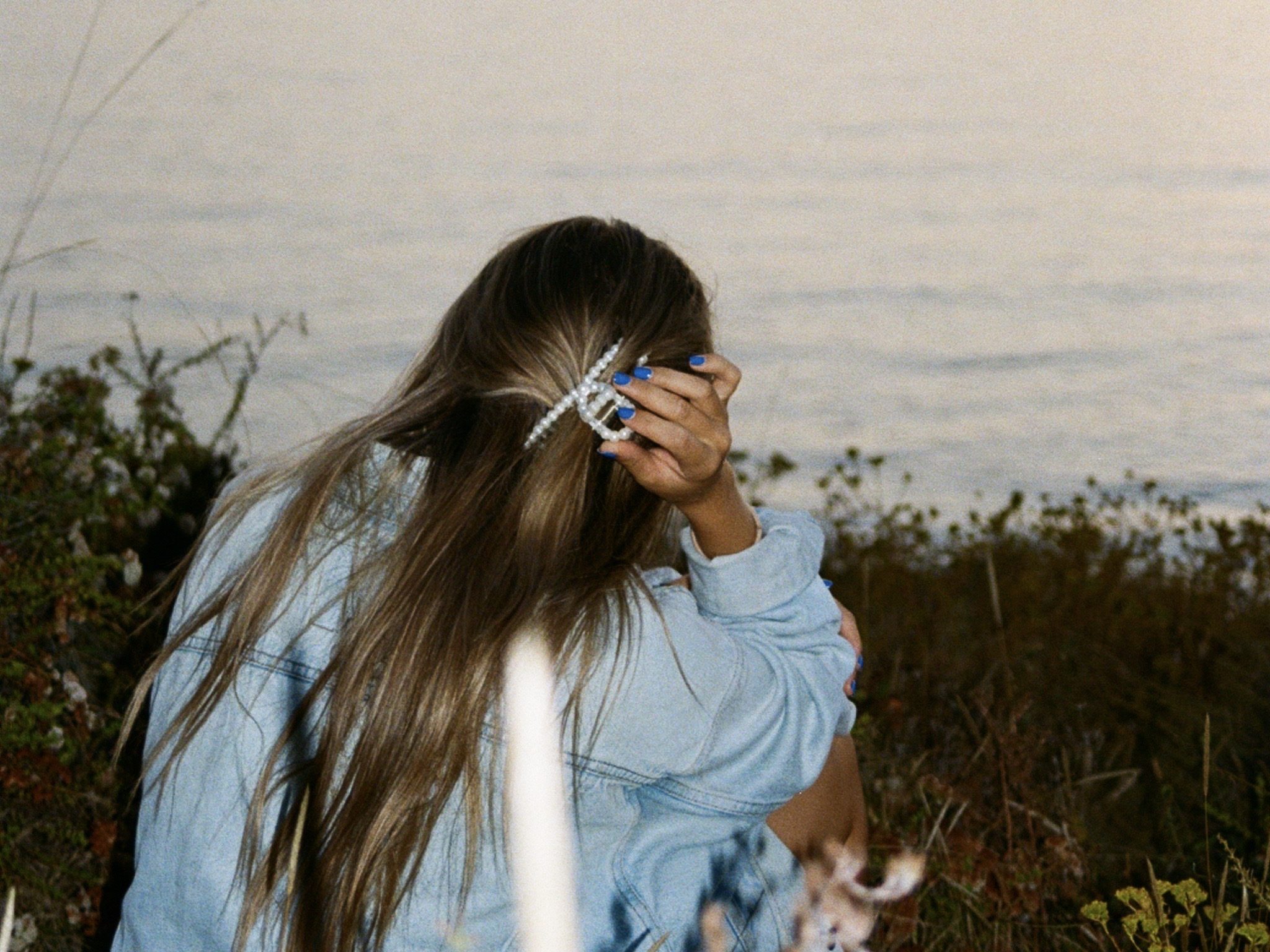 Woman at the ocean with claw clip and denim jacket — living intentionally in your 40s.